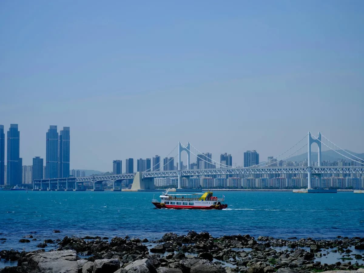 A ferry travels past a city and bridge.
